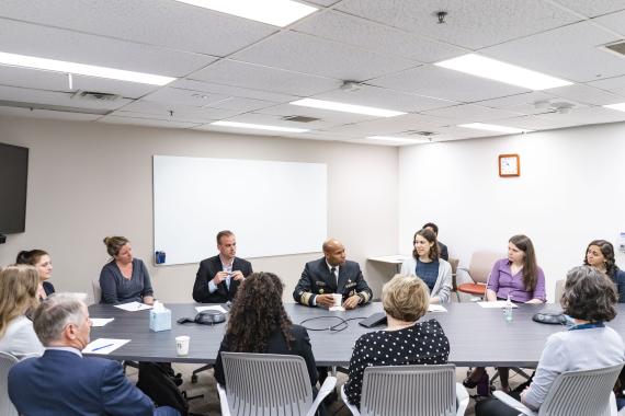Geography Graduate Student Emma Gause, U.S. Surgeon General Dr. Jerome Adams, and others sitting around a conference table.