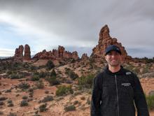 Mike Mamic stands in front of a desert landscape at Arches National Park