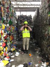 A geography intern standing in the middle of recycled materials. 