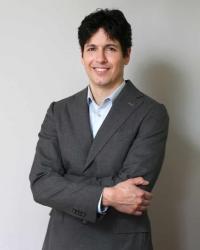 Portrait of Spencer Cohen wearing gray suit with arms crossed